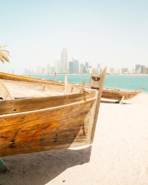Abu Dabi silueti, Birleşik Arap Emirlikleri 'nin Abu Dabi kentindeki Heritage Village' da geleneksel balıkçı tekneleriyle birlikte. Çift plajın keyfini çıkarıyor ve BAE 'deki turistik yerleri ziyaret ediyor.