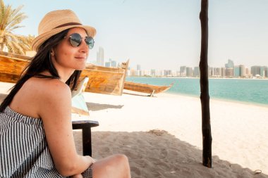 Genç bayan ziyaretçi Abu Dabi 'deki Emirlik Mirası köyünde rahatça oturuyor. Gizli mücevher, geçmişteki cazibesinden uzakta. Geleneksel Emirati yaşamının köyü, tarihi mimarinin sergilendiği, el sanatları