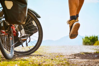 Yol kenarındaki bisikletçi kameraya ve bisikletine poz vererek havaya fırladı. Yaratıcı, ilham verici seyahat aksiyon fotoğrafı. İlham verici, ekstrem spor fotoğrafçılığı..
