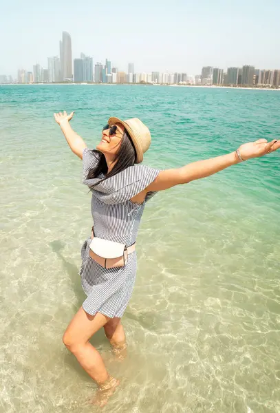 Sahil kenarında turkuaz bir gülümsemeyle uzanmış zarif genç kadın kolları sıcak bir günde ferahlatıcı suyun tadını çıkarıyor ünlü tatil beldesi Abu dhabi, BAE, Orta Doğu.