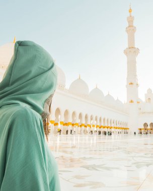 Abaya, Abu Dabi 'deki Şeyh Zayed' in Büyük Camii 'nde seyahat ederken, Müslüman elbisesi giymiş bir turist kız fotoğraf çekiyor.