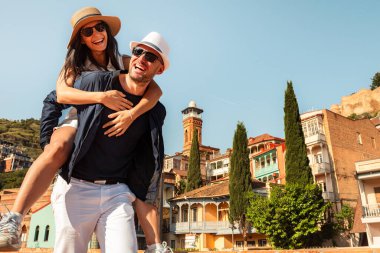 Romantik Çiftler tatilde Tiflis sokaklarında gezerken eğleniyorlar. Mutlu arkadaşlar tatilde birlikte gülerler - insanlar ve tatil kavramı. Kadını taşıyan adam birlikte zaman geçirmekten hoşlanır.