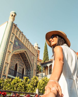 Tiflis Orbeliani Hamamları önünde eş tutan mutlu turist kadın ziyaretçi, Abanotubani bölgesinde renkli mimarinin keyfini çıkarıyor. Konsept: seyahat, bağlantı, güven. Blogger fotoğraf yardım noktası