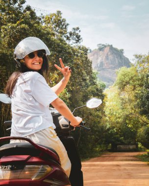 Kiralık scooter ile Pidurangala 'ya giden beyaz kadın turist pozu. Sri Lanka' da yolculuğun tadını çıkar. Asya 'daki tek başına seyahat macerası kırsal bölgeleri bağımsız olarak keşfediyor. Seyahat Sri Lanka kavramı
