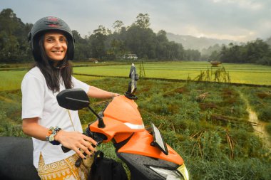 Kiralık scooter 'la yükselen tarlalarda mutlu beyaz kadın turist pozu. Sri Lanka kırsalında iyi yolculuklar. Asya 'daki tek başına seyahat macerası kırsal bölgeleri bağımsız olarak keşfediyor. Seyahat Sri Lanka kavramı