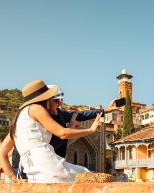 Mutlu çift Tiflis 'in eski şehir binaları kükürt banyosu önünde selfie çekiyor iki turist Georgia' da yaz tatilinde eğleniyor tatiller ve seyahat yaşam tarzı konsepti.