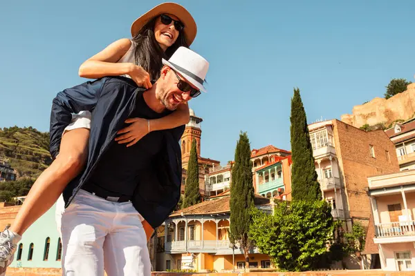 Tatilde Tiflis 'in eski sokaklarında yürüyen birkaç beyaz turist tatilde birlikte gülen mutlu arkadaşlar, insanlar ve tatil konsepti. Renkli eski şehir Tiflis binaları