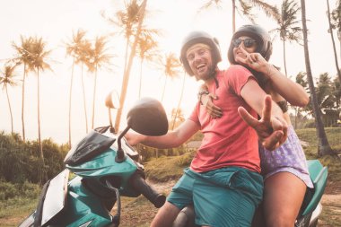 Mutlu beyaz çift, Asya 'da tatil yaparken V işaretini göstermek için sahilde kiralık mavi scooter' da poz veriyor. Sri Lanka konseptinde özgürlük macerası gezisi.