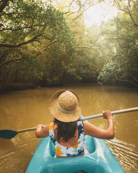 Beyaz kadın, çift mavi kano ile ön koltukta oturuyor. Sri Lanka 'nın güneyindeki Tangalle Gölü' nün sakin sularında, yemyeşil mangrovlar ve tropikal doğayla çevrili birkaç kano. Kano Macerası