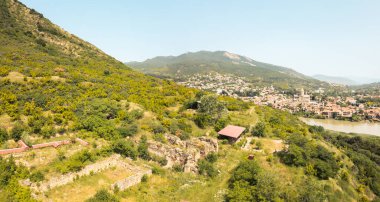Armaziskhevi 'nin panoramik hava manzarası Mtskheta kasabası, Svetitskhoveli Katedrali ve yaz mevsiminde Kafkasya tepelerini çevreleyen harabeleri ile harabe.