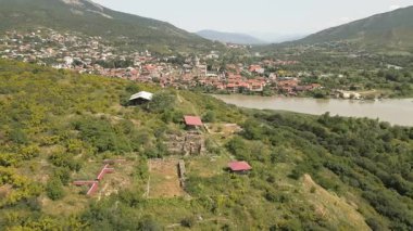 Armaziskhevi 'nin panoramik hava manzarası Mtskheta kasabası, Svetitskhoveli Katedrali ve yaz mevsiminde Kafkasya tepelerini çevreleyen harabeleri ile harabe.