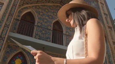 Renkli İslami mimari mimarisi Farsça cami binasının haritasıyla gülümseyen kadın turist. Seyahat planlama, kültürel keşif, tek başına yolculuk, miras macerası.