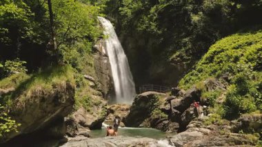 Lahodekhi, Gürcistan - 11 Mayıs 2025: Ninoskhevi Şelalesi 'nin ziyaretçi görüntüsü yemyeşil bir ormanın içinden geçerek Gürcistan' ın Lagodekhi Korunan Bölgeleri 'ndeki kayalık bir havuza akıyor.