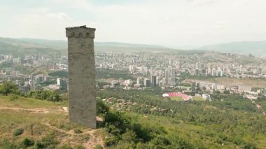 Hava panoramik manzarası Turtle Gölü 'nün üzerindeki antik Svan savunma kulesi, Vake ilçesi ve Tiflis ufuk çizgisinin kentsel büyümesine bakıyor.