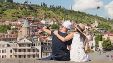 Mutlu Avrupalı turist çifti, Narikala Kalesi, Gürcistan Ana heykeli, teleferikler ve güneşli yaz gününde renkli Sololaki yamaçlarındaki evlerle Tiflis 'in eski kasabasında selfie çekiyor.