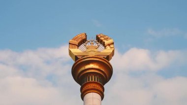 Dushanbe 'deki Tacikistan amblemi ile Stele' nin en üst amblemini kapat. Taç, yedi yıldız, buğday, pamuk, güneş, devleti, egemenliği, refahı, tarımı, birliği, liderliği sembolize ediyor