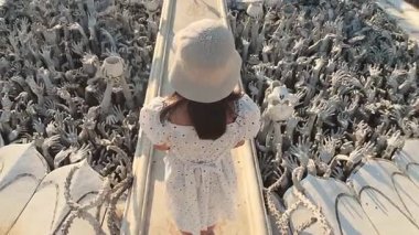 Chiang Rai, Tayland - 2024 Wat Rong Khun Beyaz Tapınağında Yeniden Doğuş Köprüsü 'nden geçen kadın. Arzunun, ızdırabın, yeniden doğuşun, karmanın, hayatın ve ölümün ruhani sembolü.