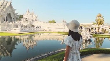 Chiang Rai, Tayland - 2024: Turist kadın gezgin Wat Rong Khun Beyaz Tapınak Chiang Rai Tayland 'ı gezerken beyaz elbiseler giyer. Seyahat blogcusu turistik ilgi odağı