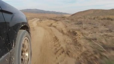 Kuru çakıllı toprak yolda giden arazi aracı. Off-road macera, özgürlük yolculuğu, açık hava keşfi, otomotiv dayanıklılığı, engebeli manzara, yaşam tarzı kaçışı ve vahşi doğa yolculuğu.