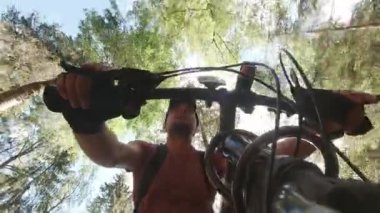 Beyaz erkek bisikletçi gülümseyerek ormanın içinde dağ bisikleti sürüyor, gülümsüyor ve eğlence, macera, özgürlük ve sağlıklı aktif yaşam tarzının tadını çıkarıyor..