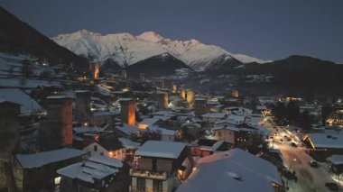 Günbatımından sonra Mestia köyünü kaplayan hava manzaralı kar, aydınlık Svan kuleleri, geleneksel mimari ve alacakaranlık gökyüzünün altındaki dağ zirveleri. Popüler kayak tatil beldesi Avrupa