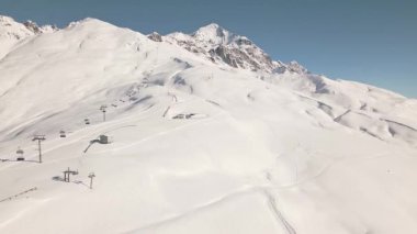 Gürcistan 'ın Svaneti kentindeki Tetnuldi Dağı' nda, temiz kış koşullarında açık mavi gökyüzü altında kar manzarası vardı. Freeriderlar tehlikeli bölge çığ riskini takip ediyor.
