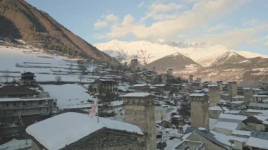Ortaçağ kuleleri ve karlı dağları manzaralı kış manzarası ile tarihi Mestia, Svaneti 'de çatıdaki Gürcistan ulusal bayrağını görüntüden uzaklaştır