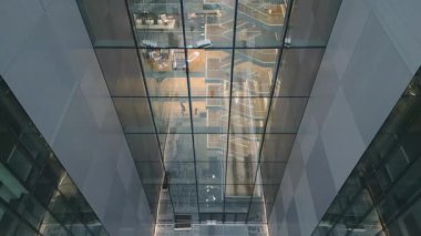 Vilnius, Litvanya - 28 Kasım 2024: hava manzaralı ofis çalışanı modern ofis içi yansımalarıyla cam iş binasında yürüyor. Anteja Tıp Kliniği. Telia telekomünikasyon şirketi