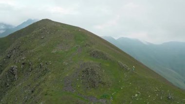 Hava manzaralı tek başına beyaz kadın yürüyüşçü Kafkasya dağlarında yavaş yavaş yokuş yukarı tırmanıyor. Sakori göl yürüyüş yolu. Kadın meydan okuması zirveye ulaşıyor