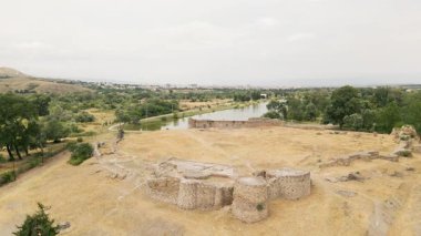 Gürcistan 'da tarihi miras ve kültür turizmini sembolize eden yeşillik ve kentsel manzaralarla çevrili antik Rustavi Kalesi manzarası üzerindeki hava sineği göl kenarındaki kalıntılar