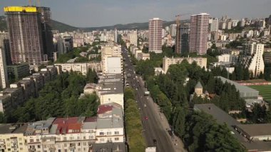 Saburtalo, Tiflis 'teki Vazha Pshavela Bulvarı' nın hava manzarasında yoğun şehir silueti, modern kuleler, Sovyet blokları ve akşam güneşinde inşaat faaliyetleri görülüyor.