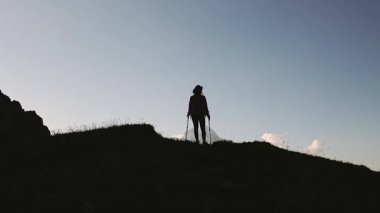 Kadın silueti, kollarını kaldırmış Kazbek Dağı 'na bakan direklerle Gürcistan Kafkasya dağlarında dağ zirvesinde gün doğumunu kutluyor. Kabarjina bakış açısı manzarası