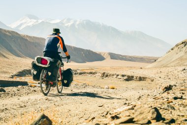 Maceracı Kafkas erkek bisikletli bisiklet Pamir 'in ücra dağlarında, çakıllı, ünlü Pamir otoyolu M41 yolunda tek başına turluyor. Pamir otoyolu macera rotası