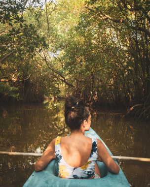 Arkadan gören kadın çift mavi kanoyla kuş gözlüyor. Sri Lanka 'nın güneyindeki Tangalle Gölü' nün sakin sularında birkaç kano, yemyeşil mangrovlar ve tropikal doğayla çevrili.