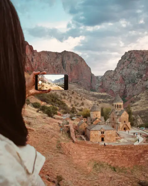 Yakın plan kadın Ermenistan 'daki Noravank Ortodoks Manastırı' nın fotoğrafını çekiyor. Kafkas dağlarındaki kırmızı renkli uçurumlarla çarpıcı bir gün batımı manzarası