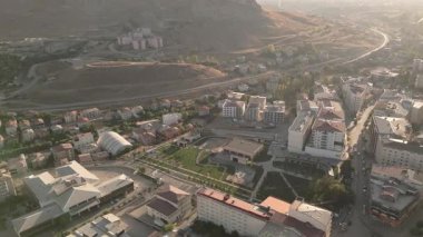 Gökyüzü panorama güneş ışığı manzaralı Van şehir parkı, yerleşim bölgesi, yeşil çimenler, ağaçlar, yollar, çevre tepeler, kentsel ufuk çizgisi, sakin akşam ışığı