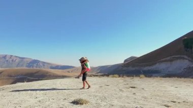 Kafkasyalı çift, mavi gökyüzü altında kurak kanyon boyunca yürür, neşeli yaz ruh hali kavramları: özgürlük, romantizm, bağ, neşe, gezinme, refah, macera, kaçış