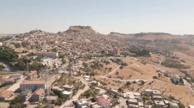 Türkiye 'nin güneydoğusunda Mardin' in eski kenti, tepede kale, dik yamaçta taş evler, kurak Mezopotamya manzarası. Geleneksel bej kireçtaşı evler ve tarihi yapılar.