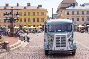 Helsinki 'de bir kaldırım taşı meydanına park edilmiş klasik bir Citroen H Van. Etrafı tarihi sarı binalar ve açık kafelerle çevrili..