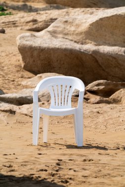 Kumlu kayalık çölde yalnız bir sandalye.