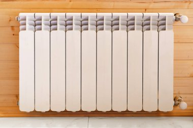 Bir kır evinin ahşap duvarında ısıtma radyatörü.