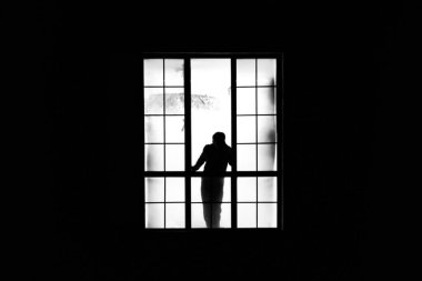 Geceleri evin penceresindeki bir adamın silüeti.