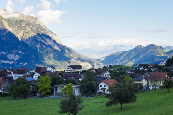 stock image Switzerland with view of houses on green grassy hills,  majestic mountains in background
