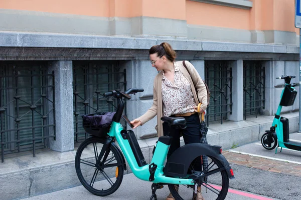 A young woman rides a bicycle for rent. Rental of bicycles and scooters. Bicycle rental service