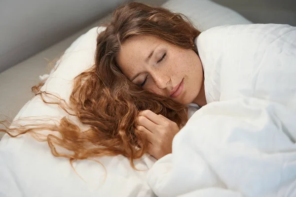 彼女の長い髪が枕の上にある間 リラックスした女性は彼女の目で閉じて眠る — ストック写真