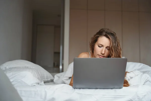 Серйозна Дама Використовує Ноутбук Спальні Поки Погляд Спрямований Клавіатуру — стокове фото