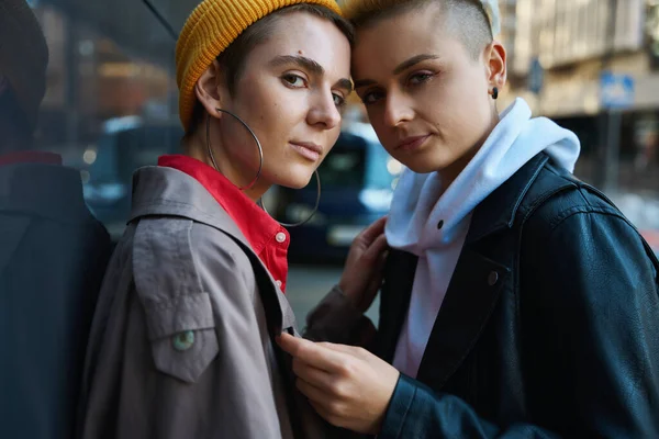 stock image Two women in city clothes are standing near wall of large building, they are calmly looking into the lens, they are couple