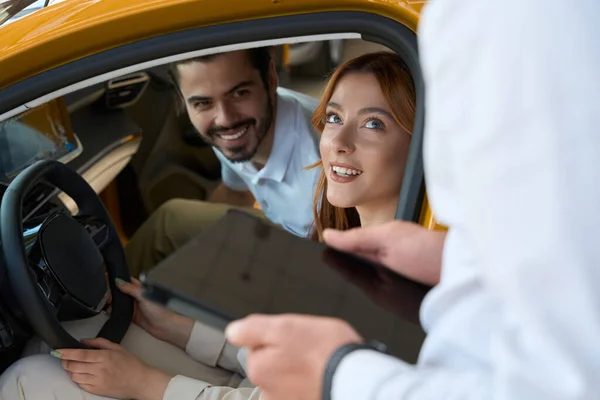 Sorridente Giovane Donna Suo Compagno Seduto Auto Guardando Venditore — Foto Stock