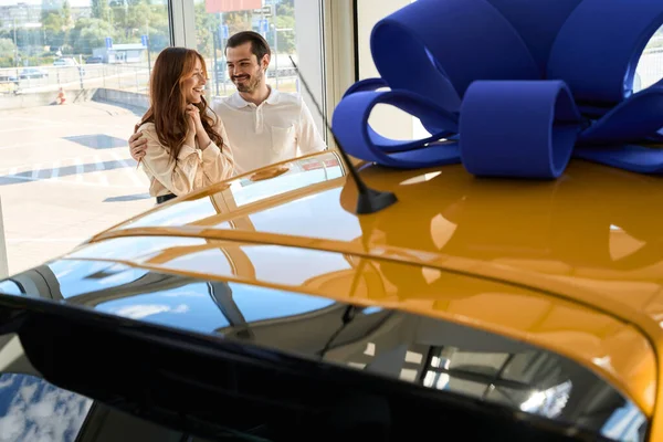愛の男へ彼の幸せな生活パートナーに新しい車を与える彼の自動車ショールームで — ストック写真