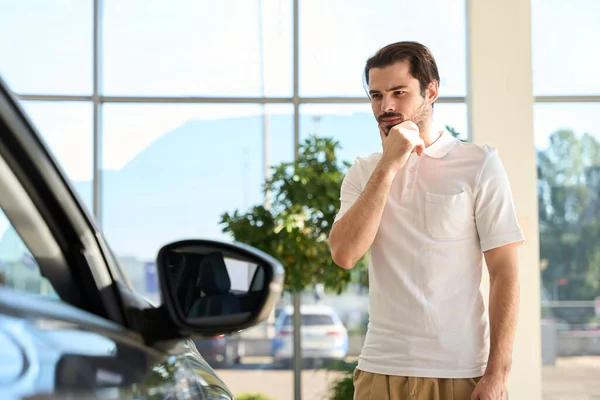 Sério Concentrado Jovem Cliente Masculino Olhando Para Carro Passageiros Showroom — Fotografia de Stock